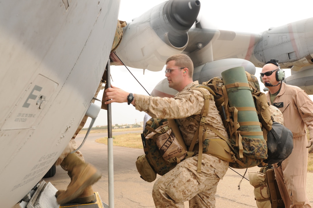 Staff Sgt. James Cook, a flight engineer with Marine Aerial Refueler Transport Squadron 234, based out of Fort Worth, Texas, guides Petty Officer 3rd Class Christopher Grigoletti, a religious program specialist with 4th Marine Division, up the ladderway onto a KC-130 during a logistics operation flight in support of Exercise African Lion 12, April 12.